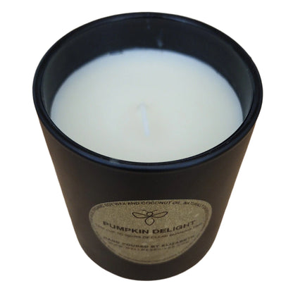 Top view of a Pumpkin Delight candle, showcasing the smooth white surface of the organic soy wax inside a black jar with a gold label. The candle is hand-poured, made from organic ingredients, and offers a clean burn.